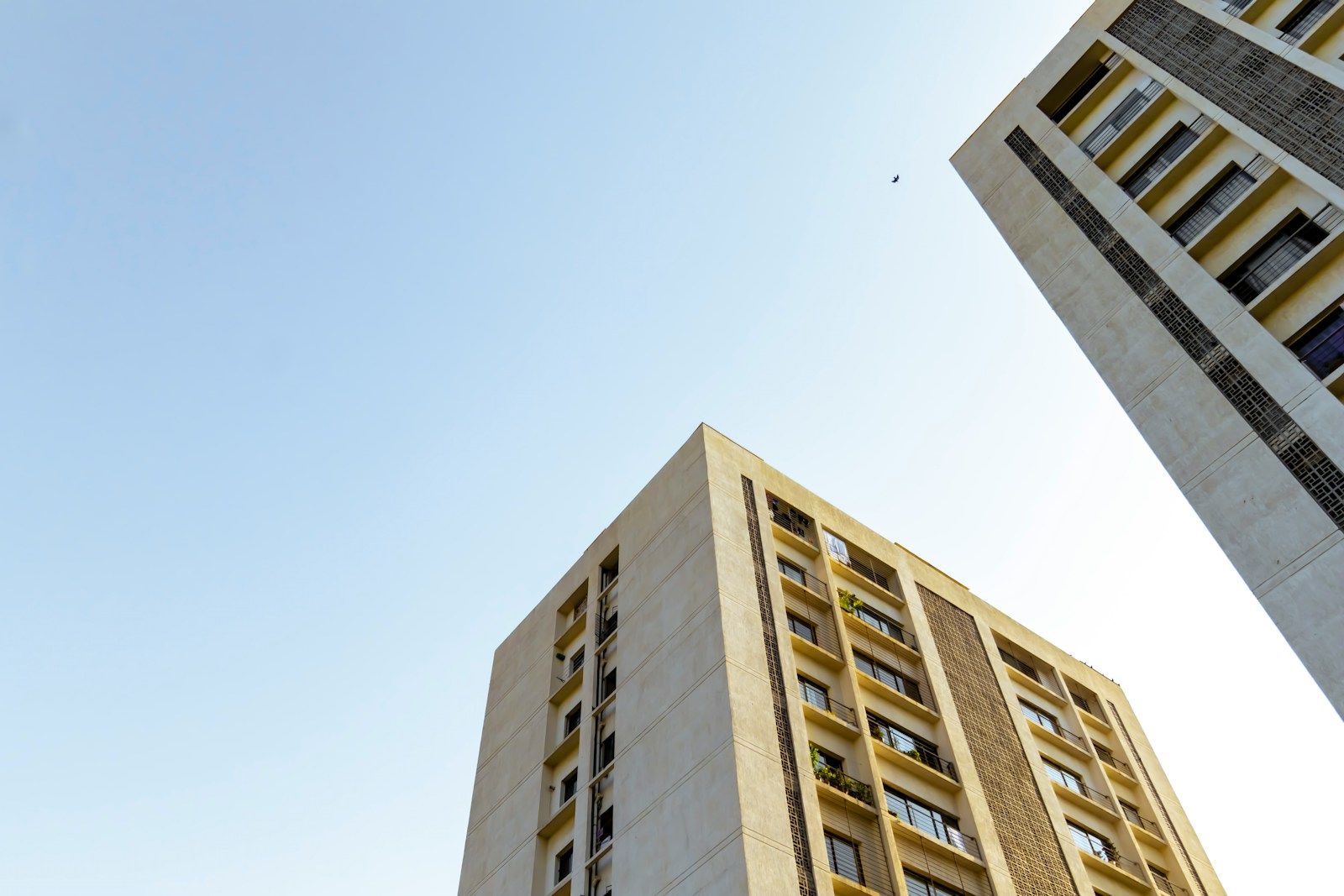 Looking up at a new apartment building with cream walls against a clear sky