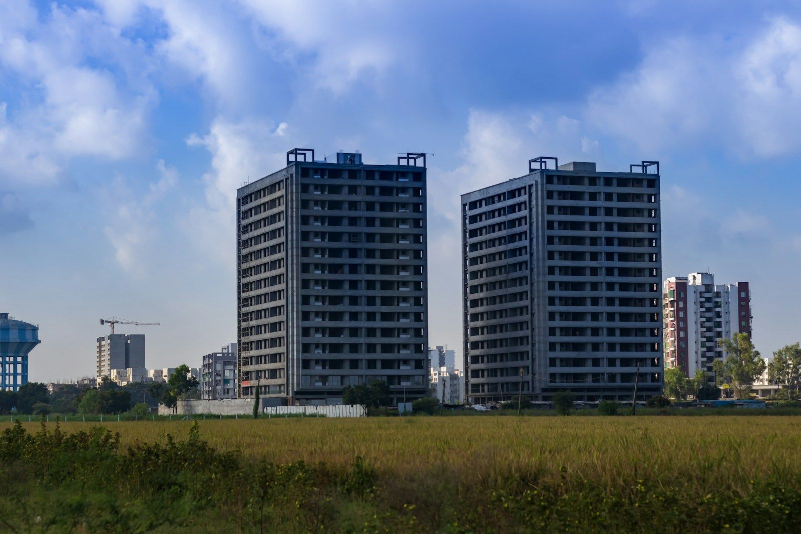 Two new residential towers on open land under a blue sky
