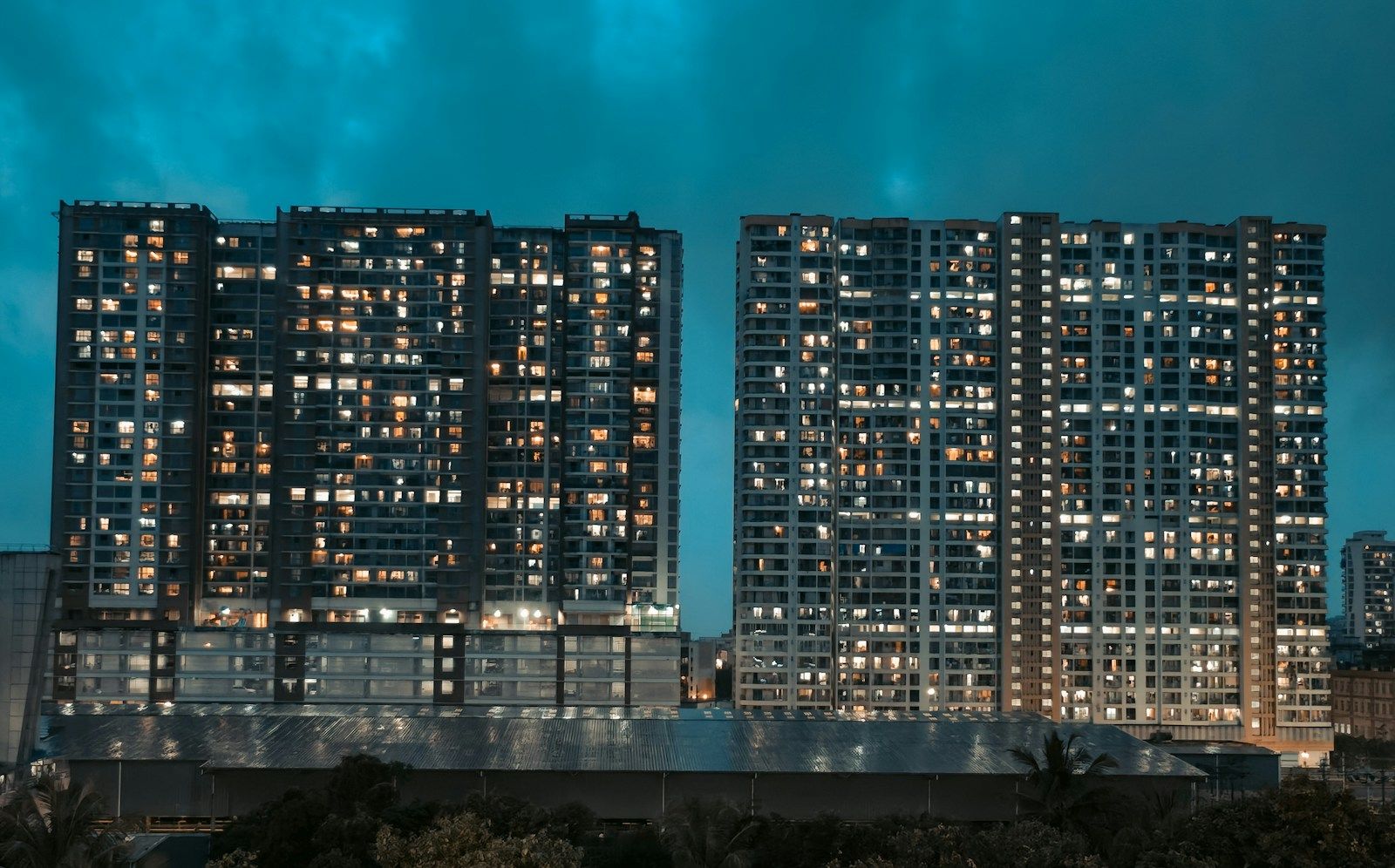 Two residential towers lit up in the evening