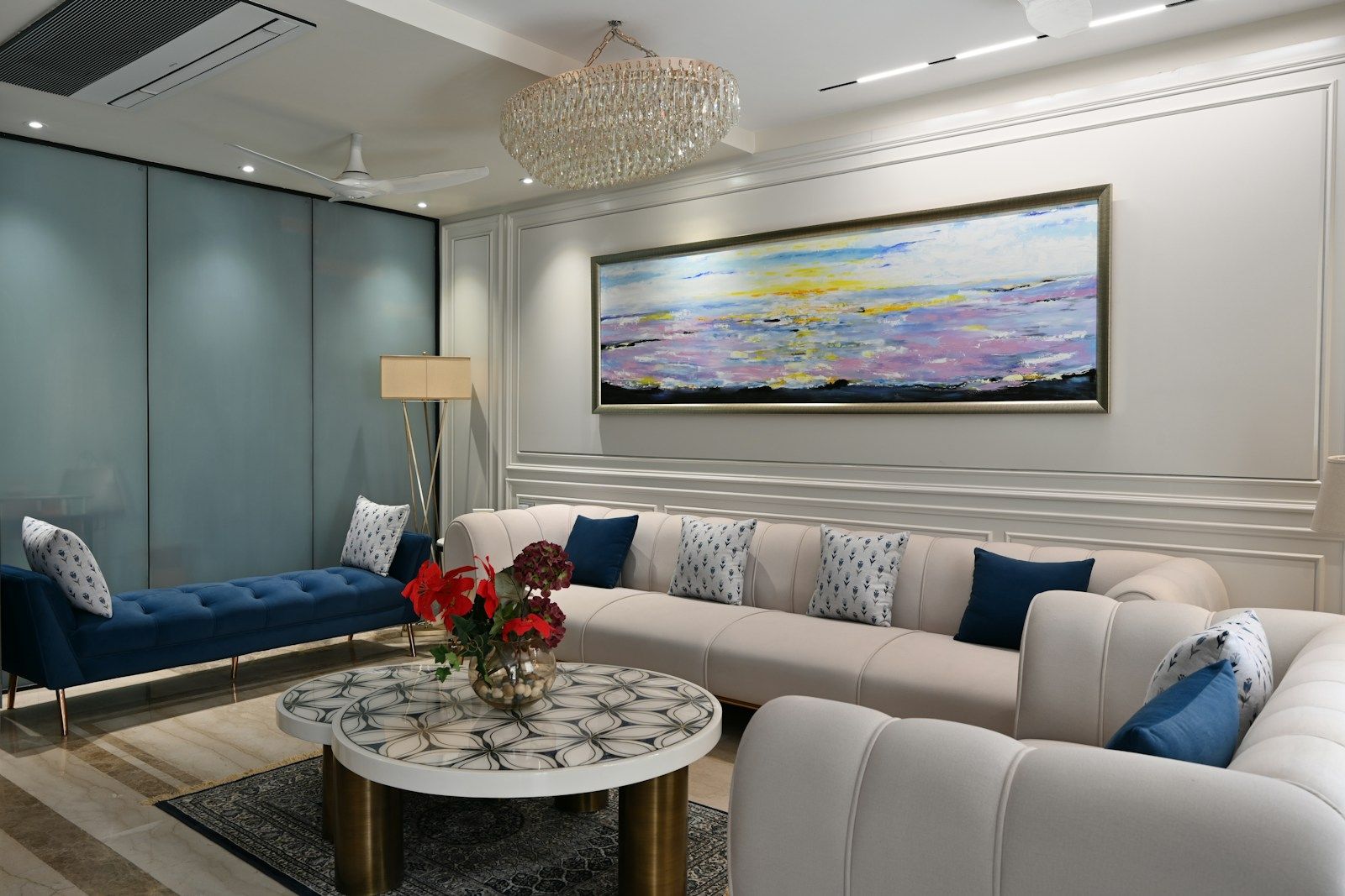 Living room with white sofas, blue cushions and a round marble table