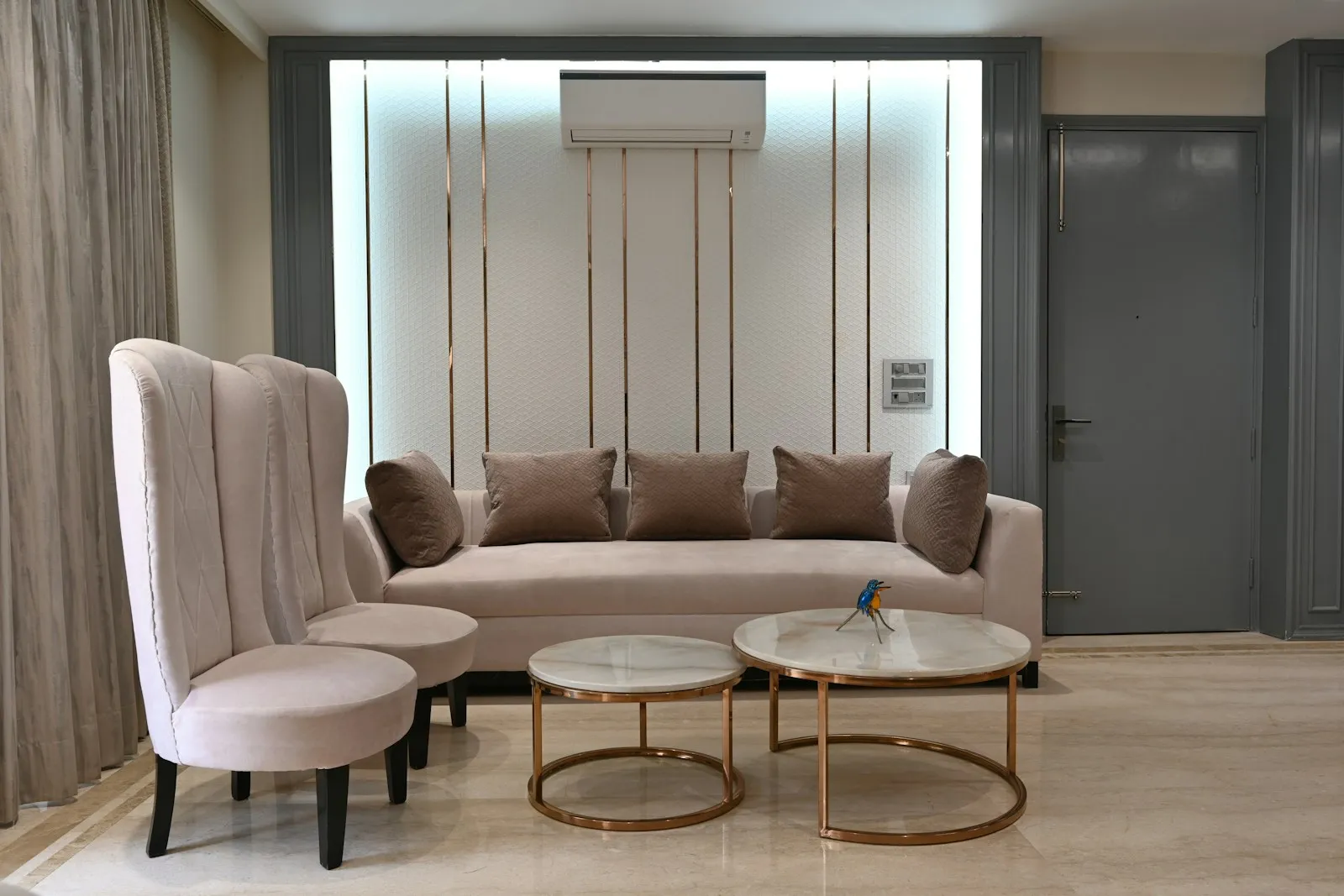 Living room with a grey sofa, a wingback chair and round side tables