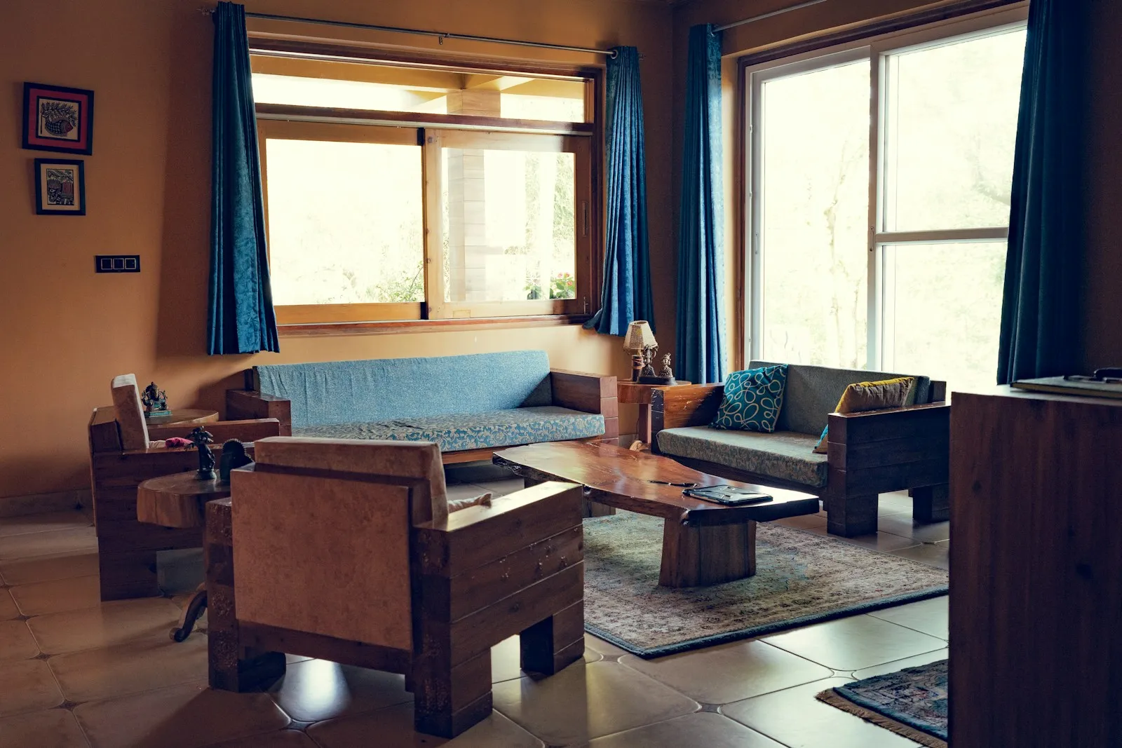 Living room with wooden chairs, a blue sofa and tall windows